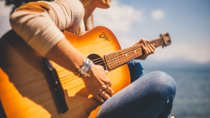 Canva - Woman Sitting Holding Guitar